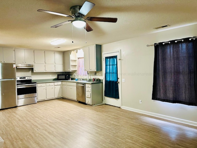 kitchen featuring stainless steel appliances, visible vents, light wood-style floors, white cabinets, and under cabinet range hood