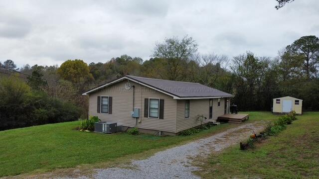 view of home's exterior featuring central air condition unit, a wooden deck, a lawn, and a shed