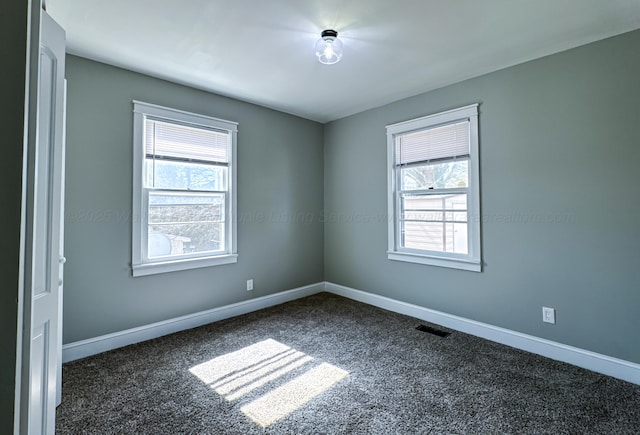 unfurnished room with baseboards, visible vents, and dark colored carpet