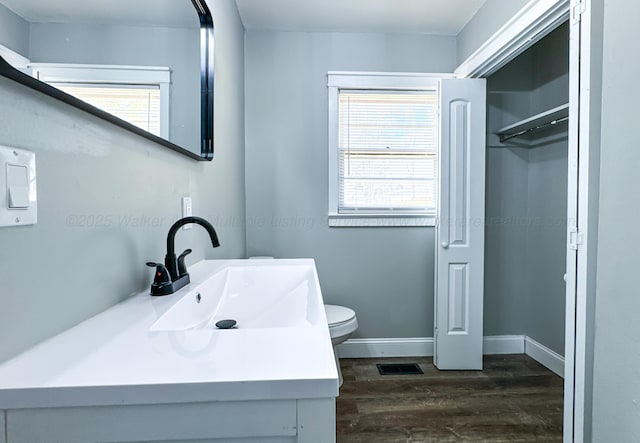 bathroom with a healthy amount of sunlight, visible vents, toilet, and wood finished floors