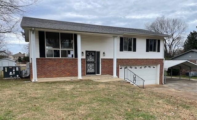 bi-level home featuring a front lawn, a carport, and a garage