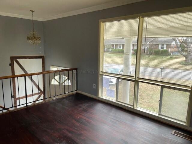 spare room featuring dark hardwood / wood-style flooring, ornamental molding, and an inviting chandelier