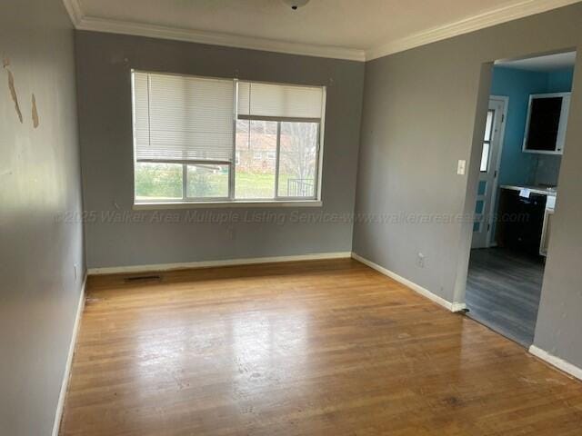 empty room with light wood-type flooring and ornamental molding