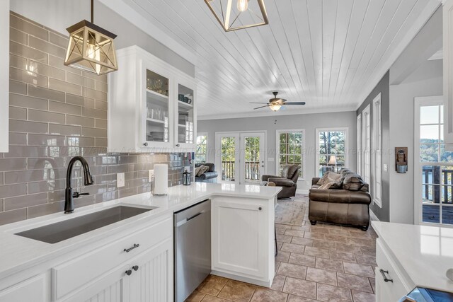 kitchen featuring pendant lighting, white cabinets, sink, stainless steel dishwasher, and tasteful backsplash