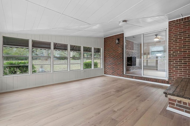 unfurnished sunroom with ceiling fan, a fireplace, and wood ceiling