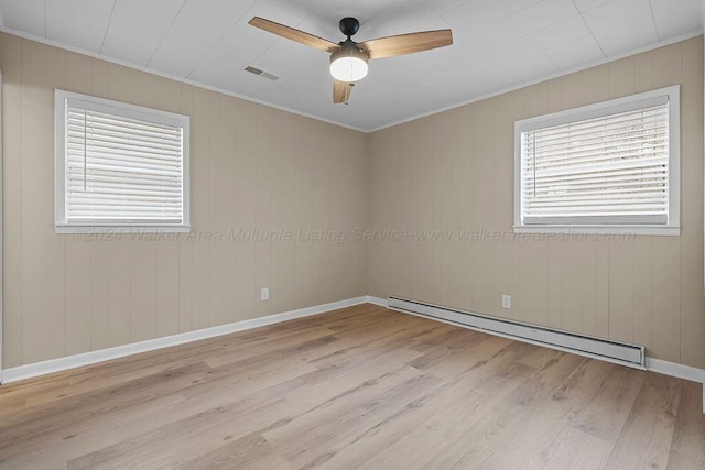 unfurnished room featuring light wood-type flooring, a baseboard radiator, ceiling fan, and wood walls