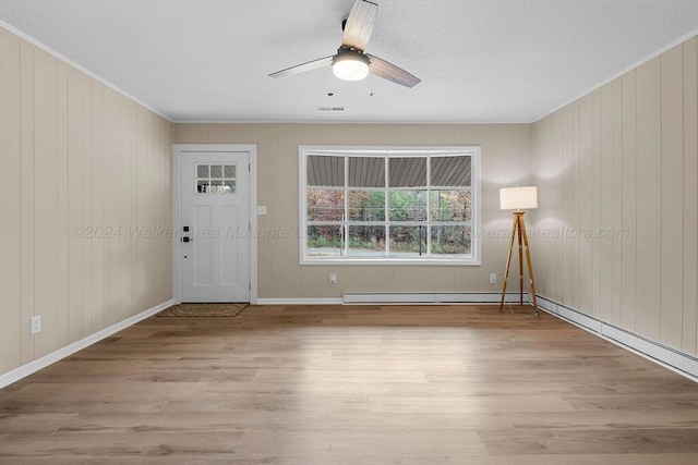 foyer entrance featuring wood walls, crown molding, light hardwood / wood-style flooring, ceiling fan, and baseboard heating