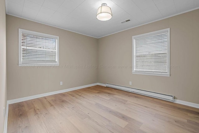 spare room featuring light wood-type flooring, crown molding, and a baseboard heating unit