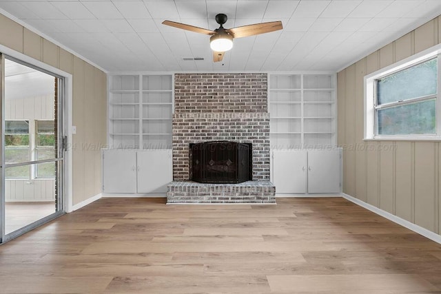 unfurnished living room featuring built in shelves, a wealth of natural light, and light wood-type flooring