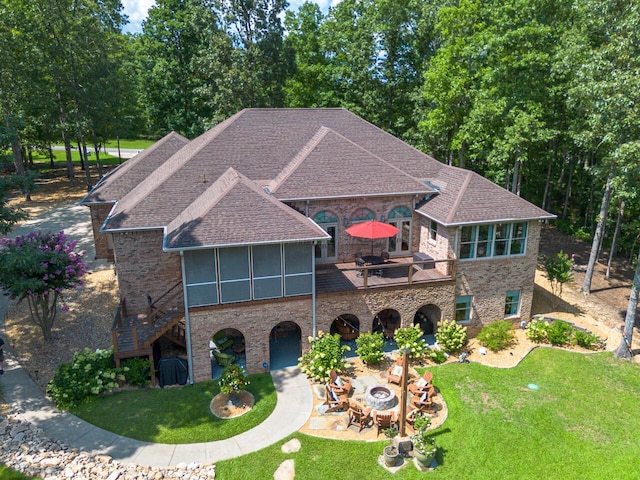 view of front of property with a fire pit, stairs, a front yard, a sunroom, and a patio