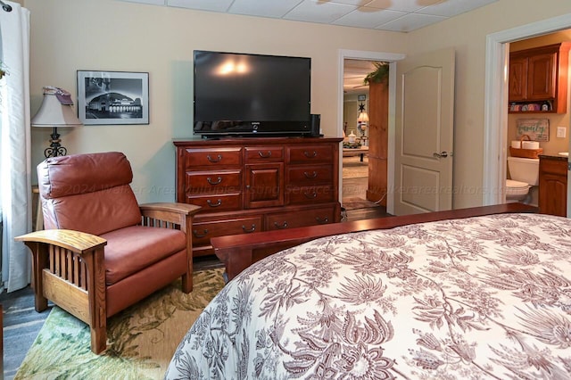 bedroom featuring a drop ceiling and connected bathroom