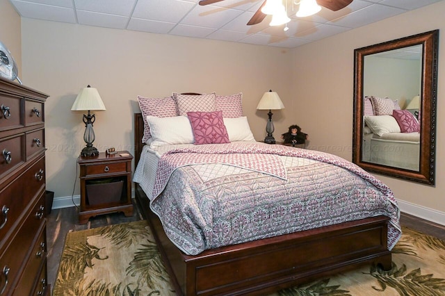 bedroom featuring ceiling fan, a paneled ceiling, baseboards, and dark wood-style flooring