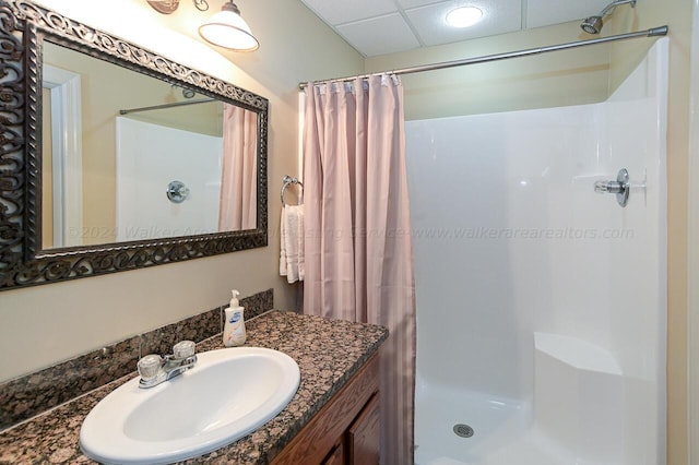 full bath featuring a drop ceiling, a stall shower, and vanity