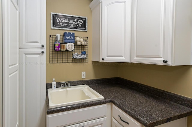 interior space featuring a sink, dark countertops, and white cabinetry