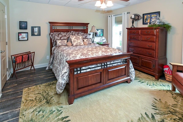 bedroom with a ceiling fan, a paneled ceiling, and baseboards