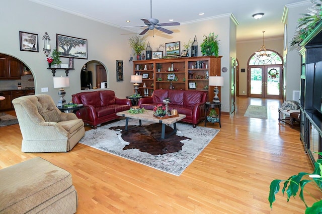 living room featuring crown molding, ceiling fan, french doors, light wood-style floors, and arched walkways