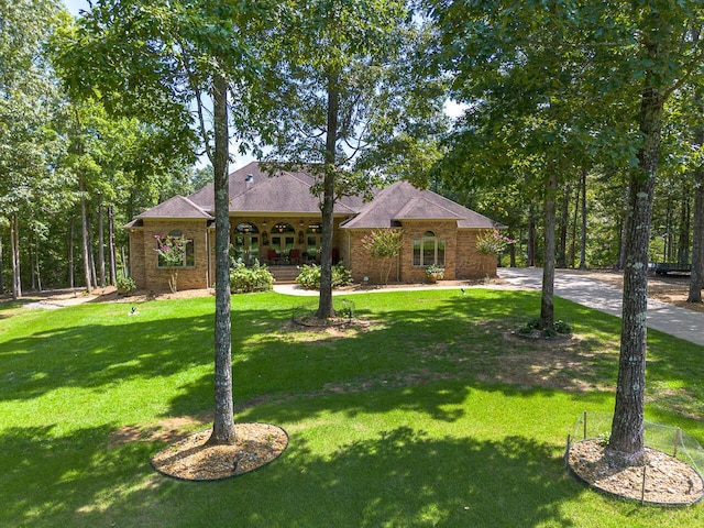 single story home featuring brick siding, a porch, and a front yard