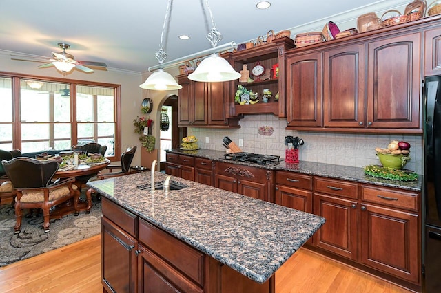 kitchen with backsplash, gas cooktop, light wood-style floors, and ornamental molding