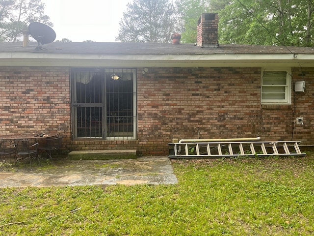 doorway to property with a yard and a patio