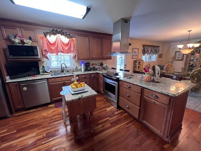 kitchen with dark wood finished floors, a peninsula, a sink, stainless steel appliances, and island range hood