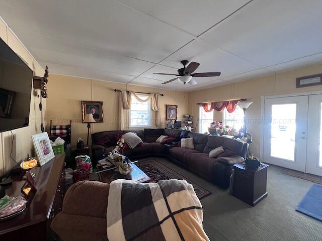 living area with a ceiling fan, carpet, and french doors