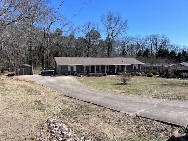 ranch-style home featuring a front yard, an outbuilding, and covered porch