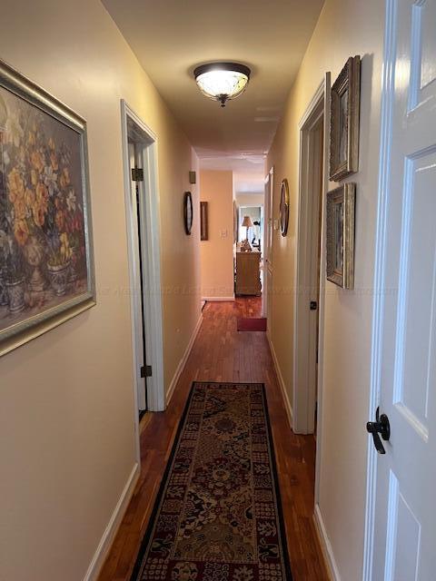 hall with baseboards and dark wood-type flooring