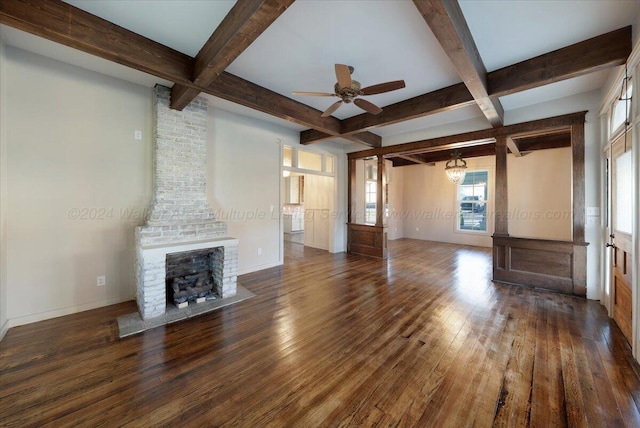 unfurnished living room with beam ceiling, dark hardwood / wood-style floors, a stone fireplace, and ceiling fan