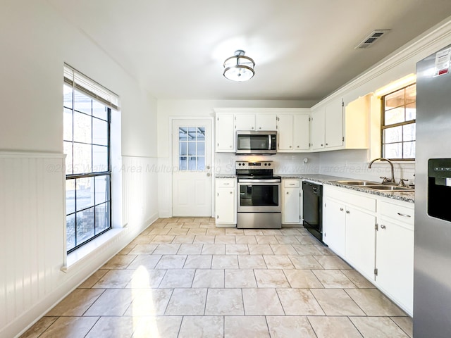 kitchen with white cabinetry, sink, light stone counters, light tile patterned floors, and appliances with stainless steel finishes