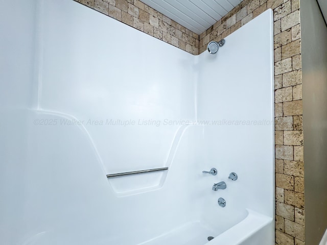 bathroom featuring brick wall and shower / bathtub combination