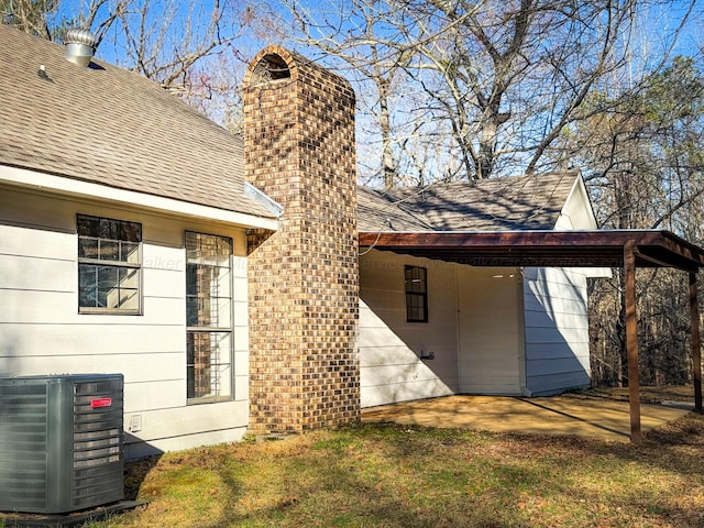 back of property featuring central AC and a carport