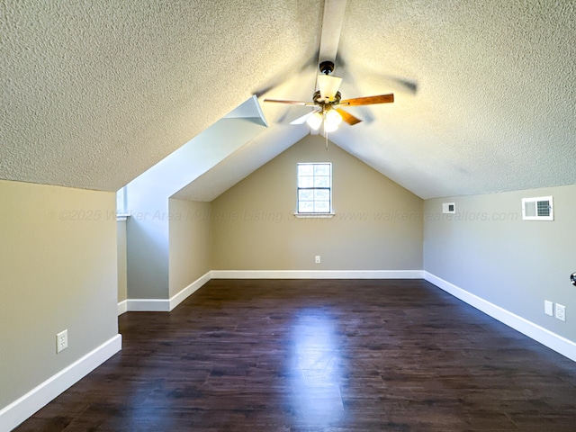 additional living space with ceiling fan, lofted ceiling, dark wood-type flooring, and a textured ceiling