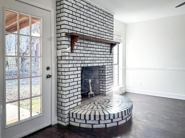 unfurnished living room featuring a brick fireplace and dark hardwood / wood-style floors