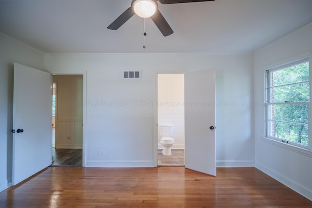 unfurnished bedroom featuring wood-type flooring, ensuite bath, and ceiling fan