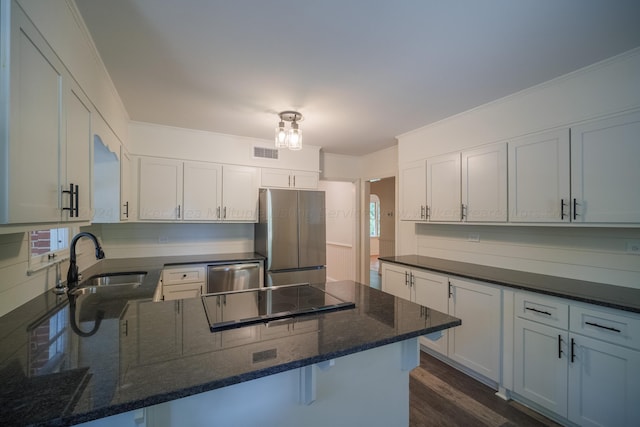 kitchen with sink, dark hardwood / wood-style floors, dark stone countertops, appliances with stainless steel finishes, and white cabinetry