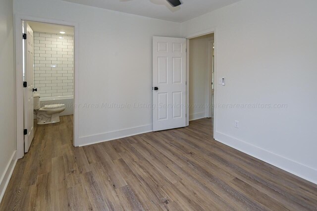 unfurnished bedroom with connected bathroom and hardwood / wood-style floors