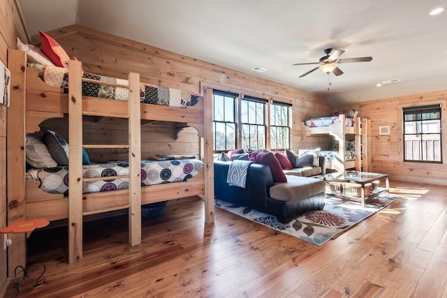 bedroom with wood walls, ceiling fan, vaulted ceiling, and hardwood / wood-style flooring