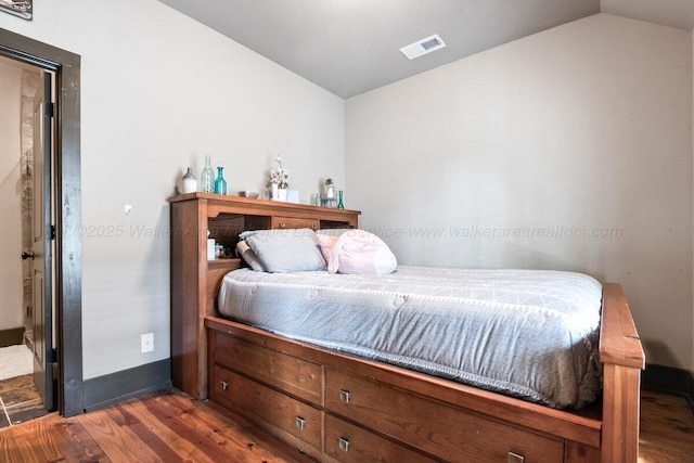 bedroom with dark wood-type flooring and vaulted ceiling