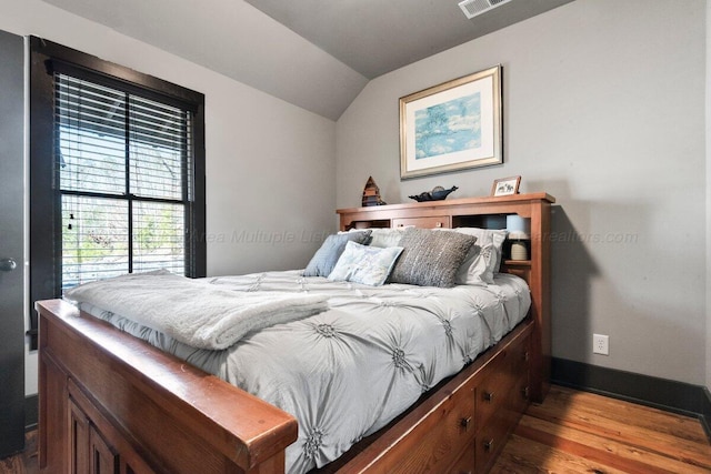 bedroom with wood-type flooring and vaulted ceiling