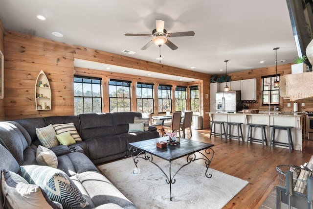 living room with sink, wood walls, ceiling fan, and dark hardwood / wood-style floors