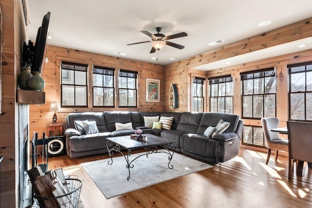 living room featuring ceiling fan, hardwood / wood-style floors, and wooden walls