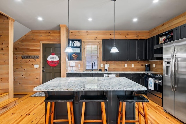 kitchen with pendant lighting, light wood-type flooring, stainless steel appliances, and a kitchen island