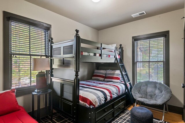 bedroom with dark hardwood / wood-style floors and multiple windows