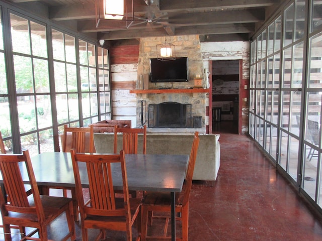 dining space with ceiling fan, a fireplace, and beamed ceiling