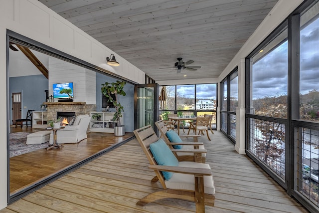 sunroom / solarium featuring ceiling fan, a fireplace, wood ceiling, and lofted ceiling