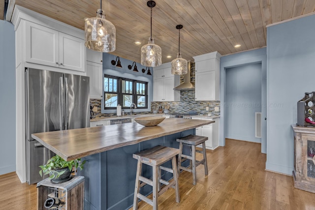 kitchen with white cabinets, a kitchen island, butcher block counters, and hanging light fixtures