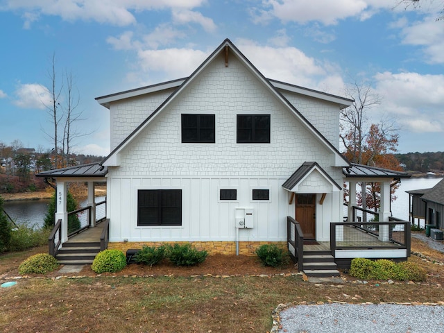 modern farmhouse style home featuring covered porch and a water view