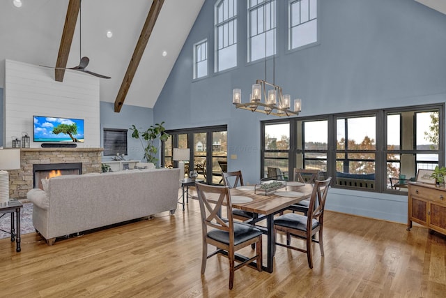 dining space with plenty of natural light, light wood-type flooring, a fireplace, and high vaulted ceiling