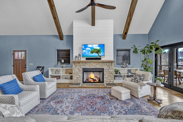 living room with high vaulted ceiling, a stone fireplace, hardwood / wood-style flooring, ceiling fan, and beamed ceiling