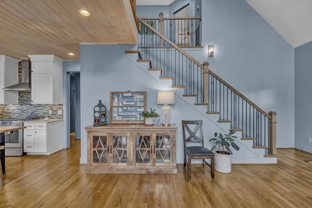 stairs with hardwood / wood-style floors, high vaulted ceiling, and wood ceiling